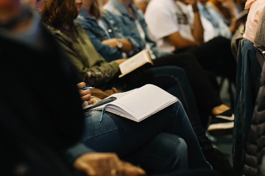 A bunch of people sitting at a conference or a workshop with their notes open.