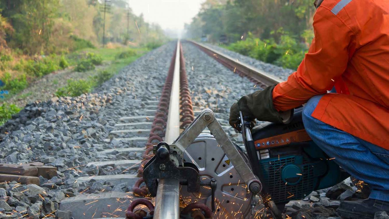 A metal power tool being used to build a railway track