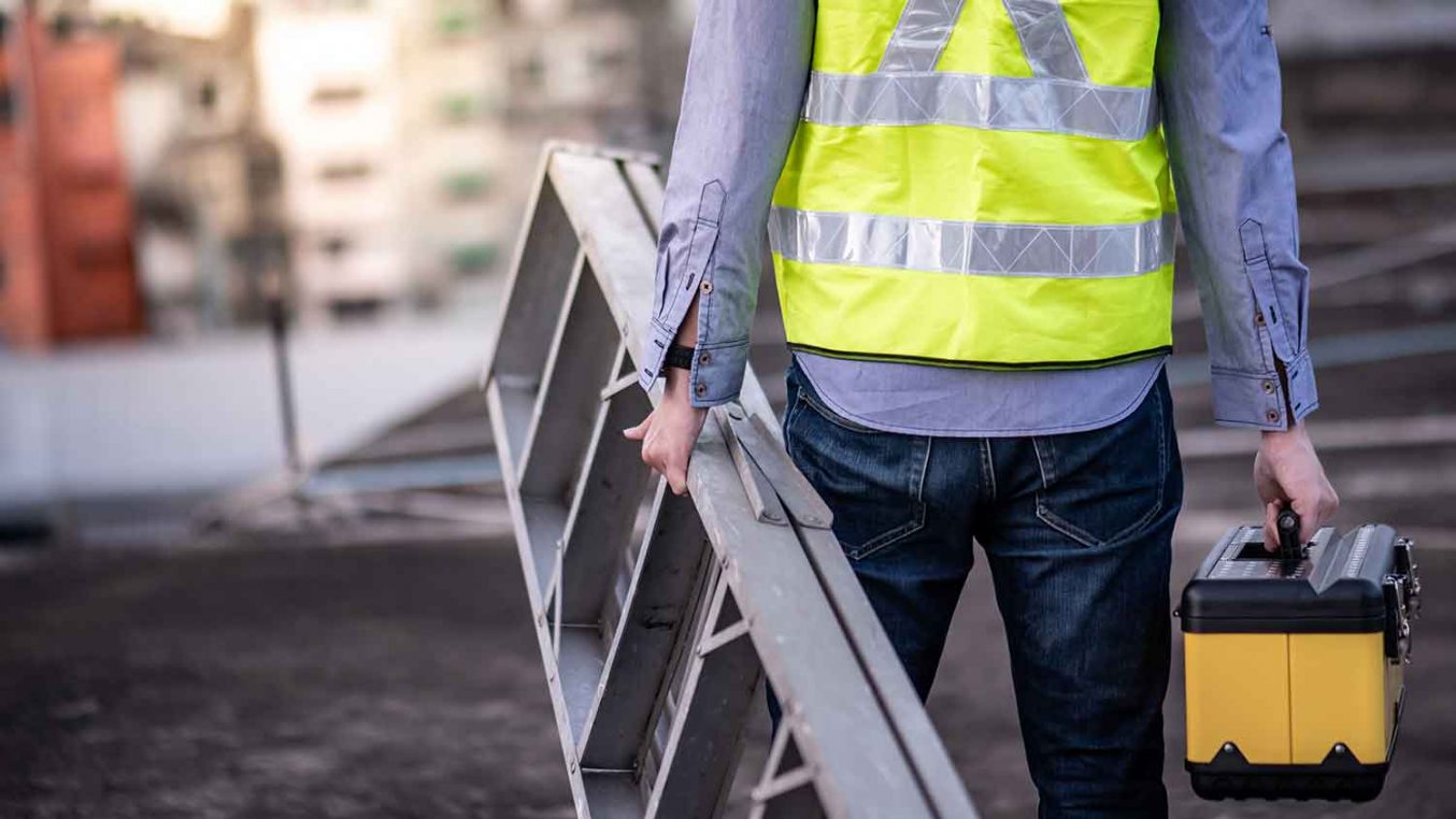 A person holding a ladder in one hand and a toolbox in the other hand