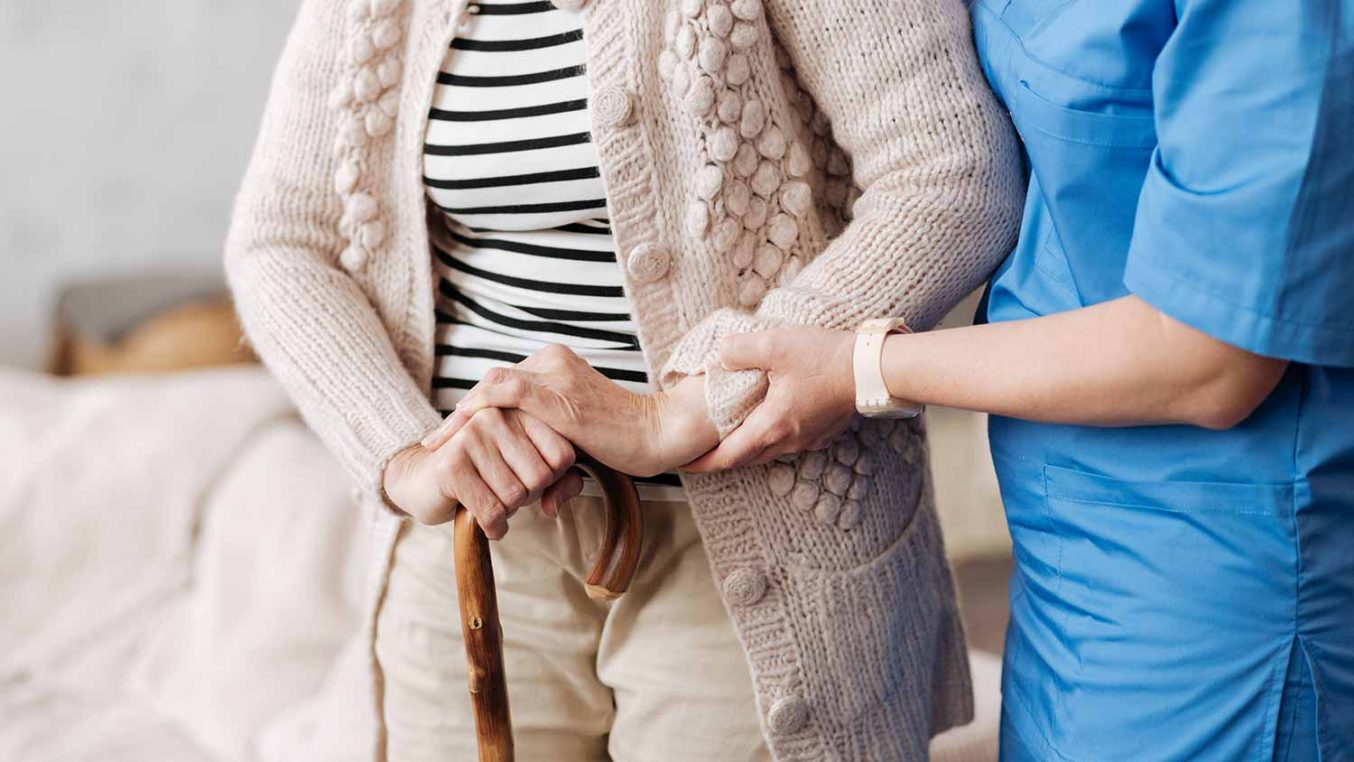 A nurse helping an elderly person whilst walking