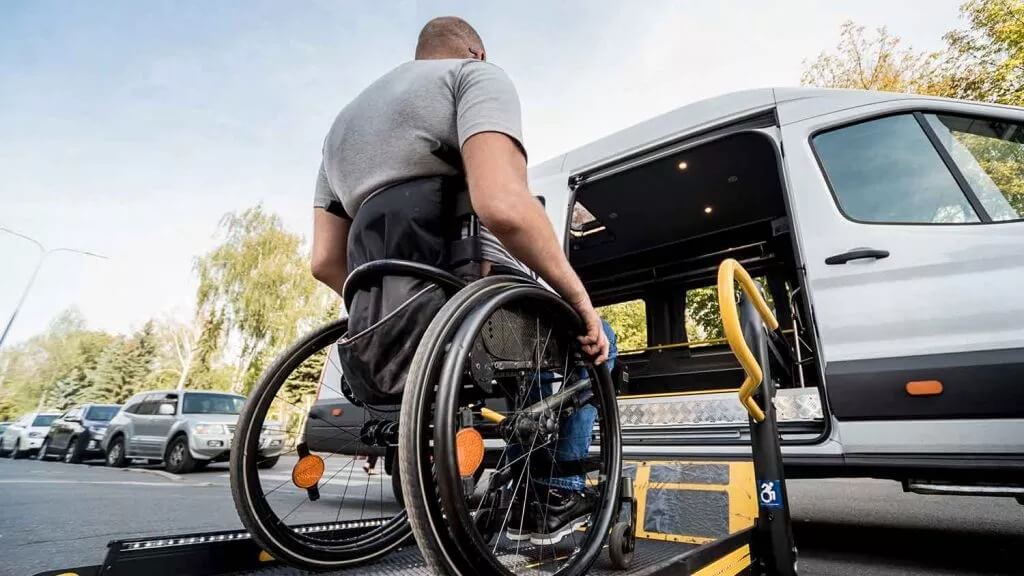A person in a wheelchair using a lift to enter a taxi