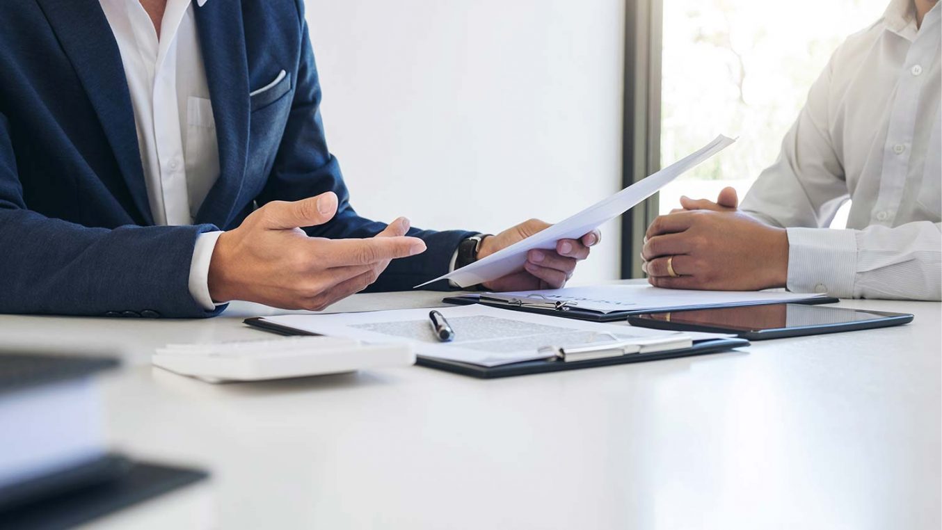 Two people sitting at a desk discussing a contract