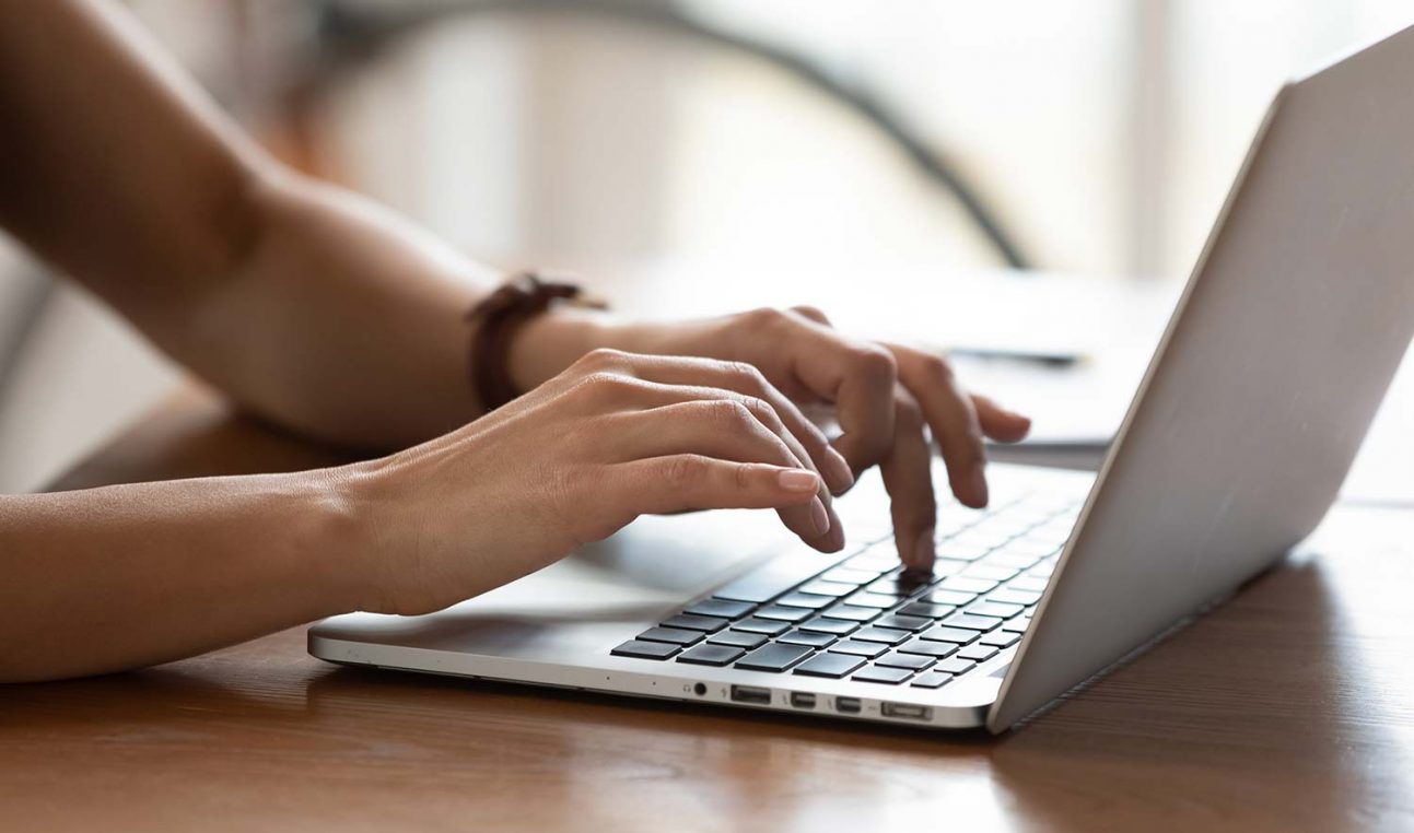 A person typing on a laptop keyboard