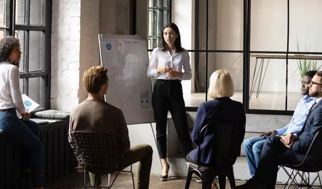 A person giving a presentation to some other people sat in a semi-circle