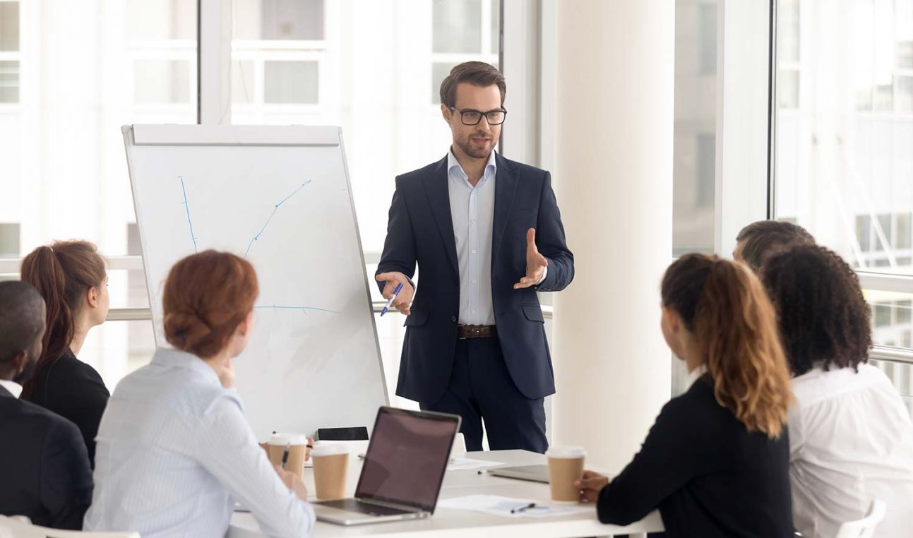 A person giving a presentation to others in front of a flipchart