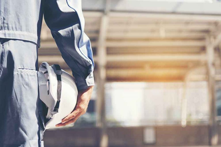 A person holding a hard hat against their hip