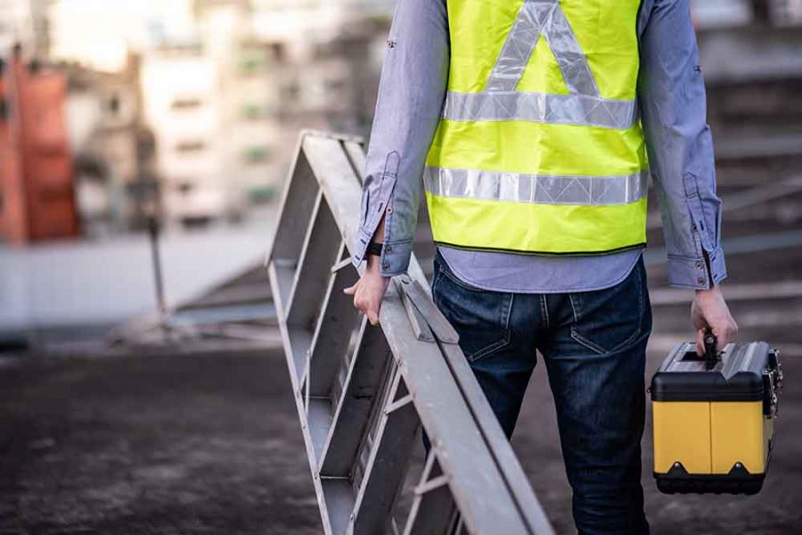 A person holding a ladder in one hand and a toolbox in the other hand