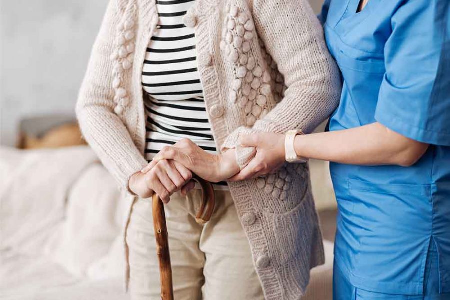 An elderly person being helped to walk by a nurse