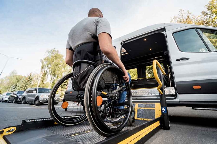 A person in a wheelchair using a lift to enter a vehicle