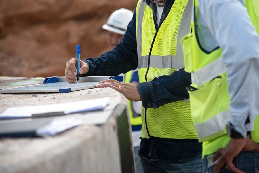 A person in a hi-vis vest writing on a whiteboard