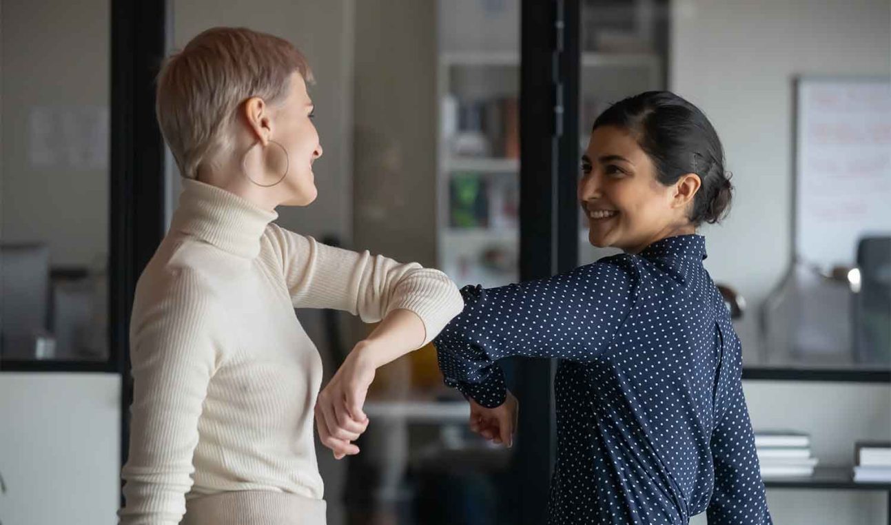 Two people using their elbows to greet each other